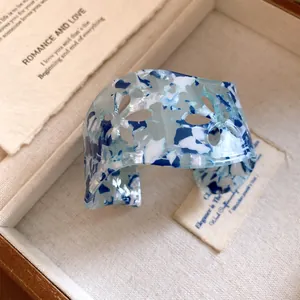 Macro view of blue marble acrylic cuff bracelet featuring delicate floral hollow cutouts