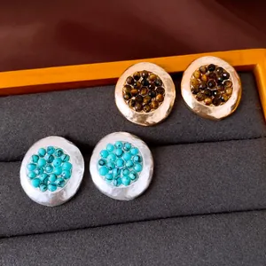 Primer plano de pendientes redondos vintage con acabado martillado y cuentas de piedra