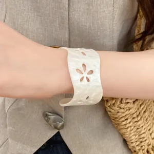 Close-up view of white acrylic acetate open cuff bracelet with hollow flower design