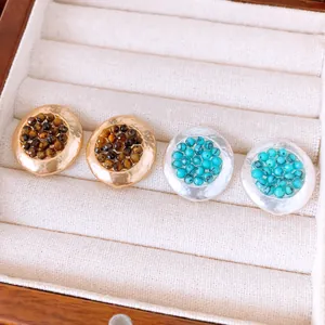 Detalle de pendientes redondos de piedra arrugada en elegantes acabados en oro y plata