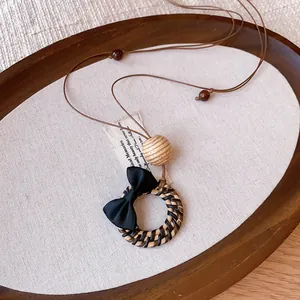 Detailed view of a bohemian woven pendant necklace with a black bow and tiger eye beads.