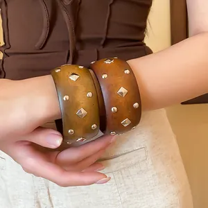 Detalle de brazaletes de madera vintage con tachuelas metálicas redondas