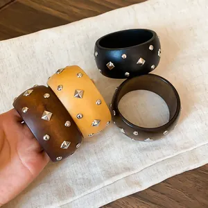 Vista detallada de brazaletes de madera retro con tachuelas metálicas en tres colores