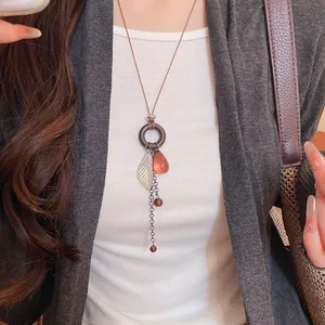 Close-up detail of bohemian tassel necklace featuring tiger eye beads and leaf pendant