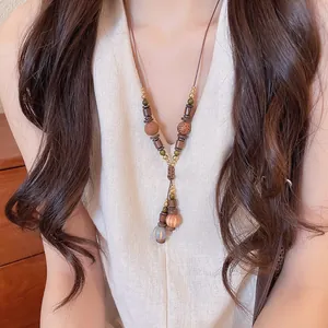 Close-up detail of bohemian tassel necklace with tiger eye stone beads worn on model