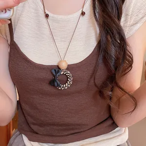 Detailed view of bohemian woven pendant necklace with black bow worn on sweater