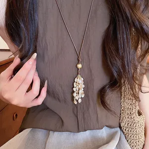 Close-up detail of a vintage bohemian shell tassel necklace worn with a brown top