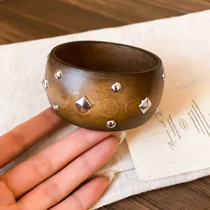 Primer plano de un brazalete de madera retro decorado con remaches cuadrados y redondos