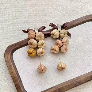 Close-up detail of Bohemian bow earrings with zircon and natural seed pendants