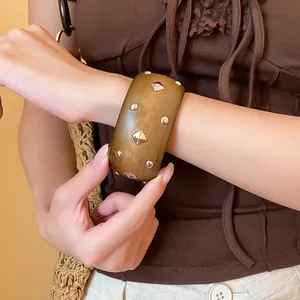 Primer plano de una pulsera retro de estilo madera con tachuelas plateadas redondas y de rombo