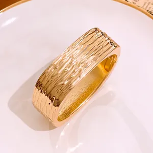 Detailaufnahme eines klobigen goldfarbenen quadratischen Armreifs mit einzigartiger Faltenstruktur