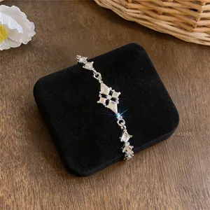 Close-up van zilverkleurige armband met fonkelende ruitvormige kristallen hangers op fluweel.