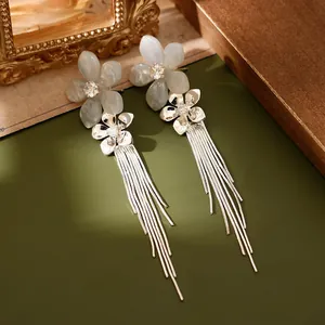 Vue détaillée de boucles d'oreilles à pompons argentés avec fleurs en résine et zircons