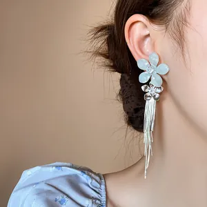 Boucles d'oreilles élégantes avec fleurs en argent et glands sur l'oreille du modèle