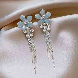 Gros plan montrant la fleur bleue et les détails en zircone sur les boucles d'oreilles