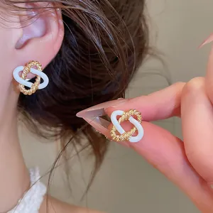Gedetailleerde weergave van elegante in elkaar grijpende goudkleurige en witte oorbellen
