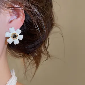 Close-up van elegante witte bloem oorknopjes met gouden details gedragen aan het oor