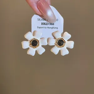 Detailopname van witte emaille bloemenoorbellen met S925 zilveren naalden op display