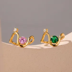 Macro view of minimalist gold wavy stainless steel rings featuring pink and green zircon