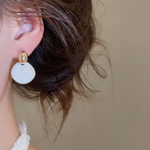 Elegante close-up van een goud en wit emaille bloemknopoorbel gedragen aan oor