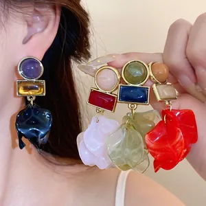 Close-up of colorful acrylic geometric petal statement earrings with silver needles.