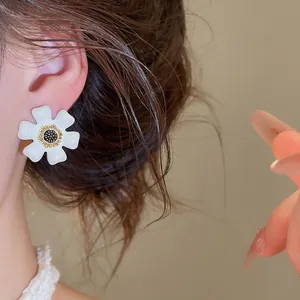 Close-up van een delicate witte emaille bloemoorbel met een hol goudkleurig midden.
