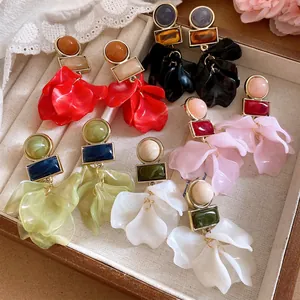 Detailed macro view of assorted colorful acrylic petal drop earrings in a jewelry box.