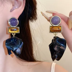 Close-up of vintage geometric acrylic flower petal earrings with purple and amber stones