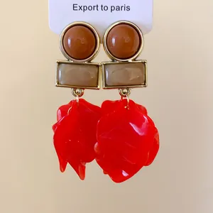 Detailed close-up of red acrylic petal drop earrings featuring geometric gold-tone studs