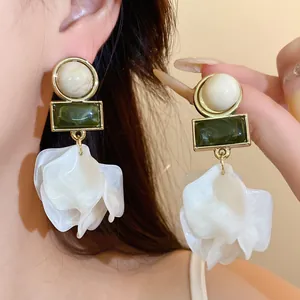 Close-up of vintage-style acrylic petal earrings with green geometric resin details