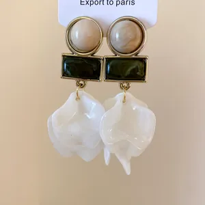 Detail view of retro geometric earrings with white acrylic petals and green resin