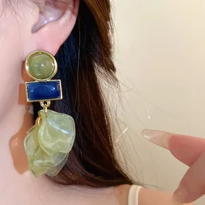 Macro close-up detail of oversized acrylic petal earrings featuring geometric shapes