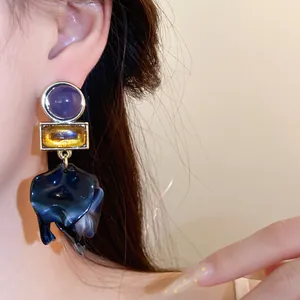 Close-up detail of large vintage acrylic petal drop earrings with purple and yellow gems