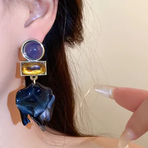 Close-up of vintage-style acrylic floral drop earrings featuring geometric gems and petals