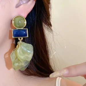 Macro view of acrylic petal earrings featuring green and blue geometric elements