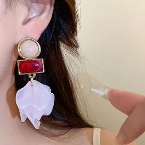 Detailed view of statement acrylic petal drop earrings with red resin and gold frames
