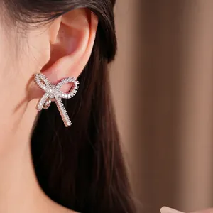 Clip d'oreille élégant en forme de nœud argenté orné de zircons étincelants sur un modèle