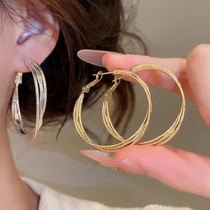 Detailansicht von eleganten, dreilagig verdrehten Creolen in Gold- und Silberoptik