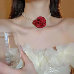 Elegante mehrlagige Perlenkette mit einer großen roten Stoffrose in Detailansicht.