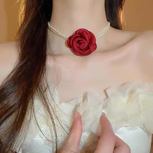 Detailansicht einer roten Stoffrose an einer eleganten, mehrlagigen Perlen-Choker-Halskette