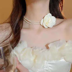 Nahaufnahme eines eleganten mehrlagigen Perlen-Chokers mit einer weißen Stoffrose-Verzierung.