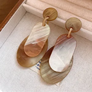 Elegante Acryl-Ohrhänger mit Marmorstruktur und Silbernadeln in einer Schmuckschatulle.
