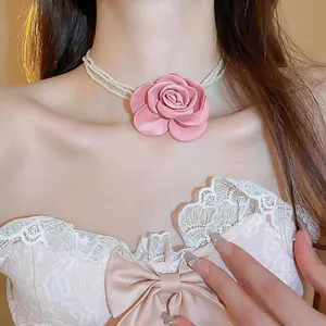 Detailansicht von rosa Stoffrose und mehrlagigem Perlen-Choker am Hals