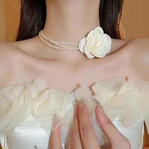Nahaufnahme eines eleganten mehrlagigen Perlen-Chokers mit weißer Stoffblume für Damen