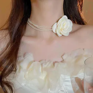 Detailansicht eines eleganten mehrlagigen Perlen-Chokers mit einer weißen Stoffrose