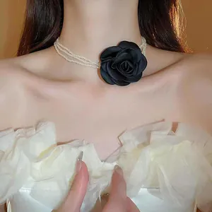 Detailansicht eines mehrlagigen Perlen-Chokers mit einer großen schwarzen Stoffrose.