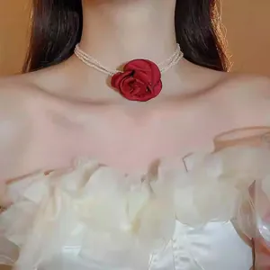 Detaillierte Ansicht eines Perlen-Chokers mit einer großen roten Stoffrose