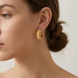 Close-up detail shot of 18K gold-plated stainless steel ribbed hoop earring on a model.