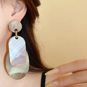 Detailansicht von mehrschichtigen geometrischen Acryl-Ohrringen mit Marmortextur