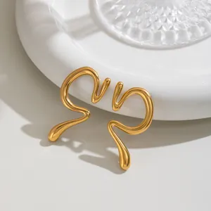 Vue macro de boucles d'oreilles minimalistes en acier inoxydable doré liquide sur plateau